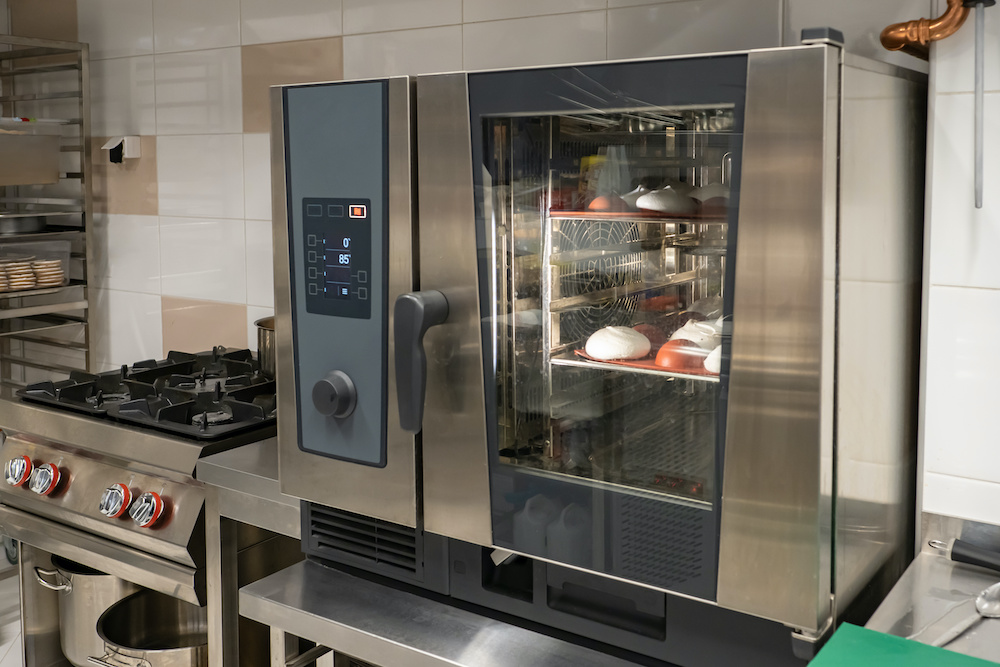 Сombi steamer in confectionery shop. Some confectionery is being prepared inside Сombi steamer. Industrial oven in restaurant kitchen. Combi steamer while cooking. Equipment for confectionery shop